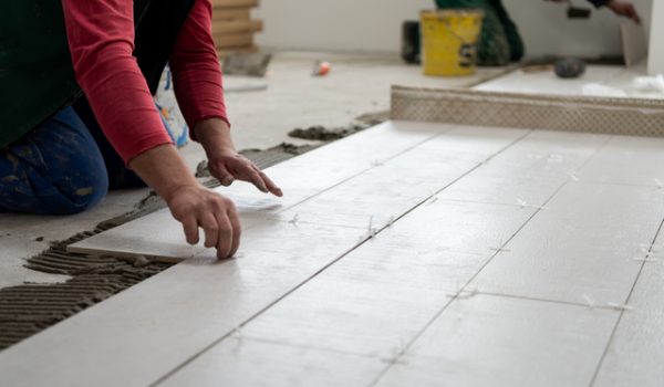 worker installing the ceramic wood effect tiles on the floor skilled worker installing the ceramic wood effect tiles on the floor Worker making laminate flooring on the construction site of the new apartment